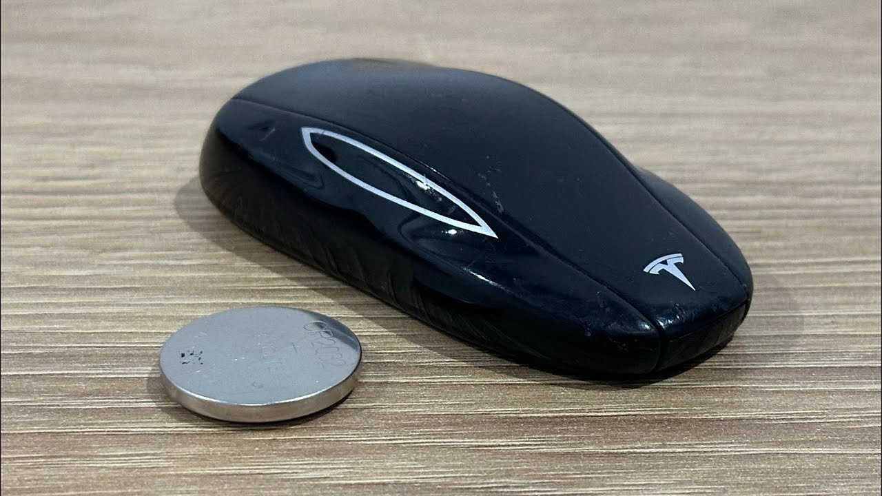 Tesla Model Y key fob with CR2032 battery compartment open showing battery replacement process and orientation