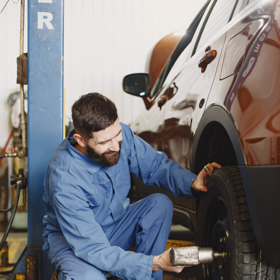 Person in safety gear preparing to jumpstart a car