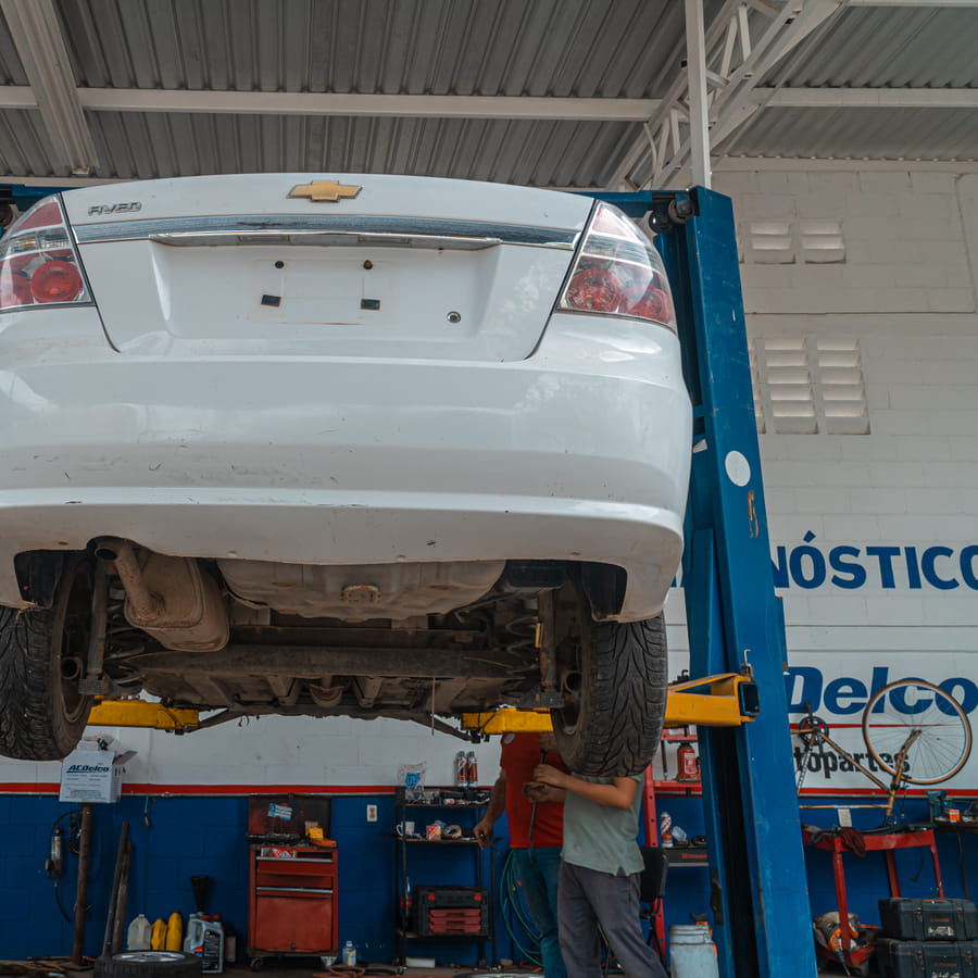 Person inspecting a car battery under the hood of a car
